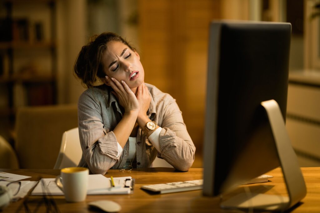 Exhausted professional continuing to work while repeatedly postponing rest.