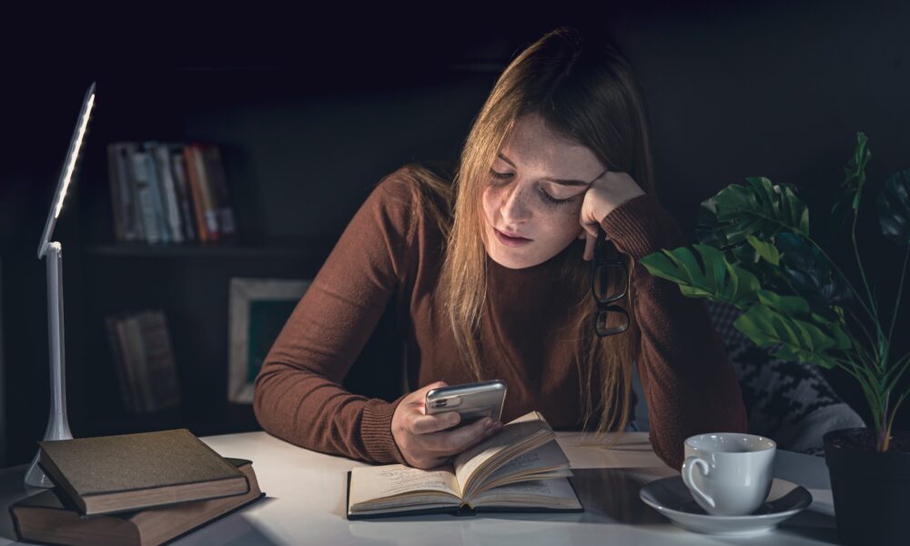 Person looking overwhelmed while sitting at a desk surrounded by smartphone notifications and digital distractions