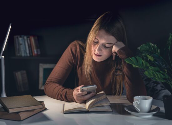 Person looking overwhelmed while sitting at a desk surrounded by smartphone notifications and digital distractions