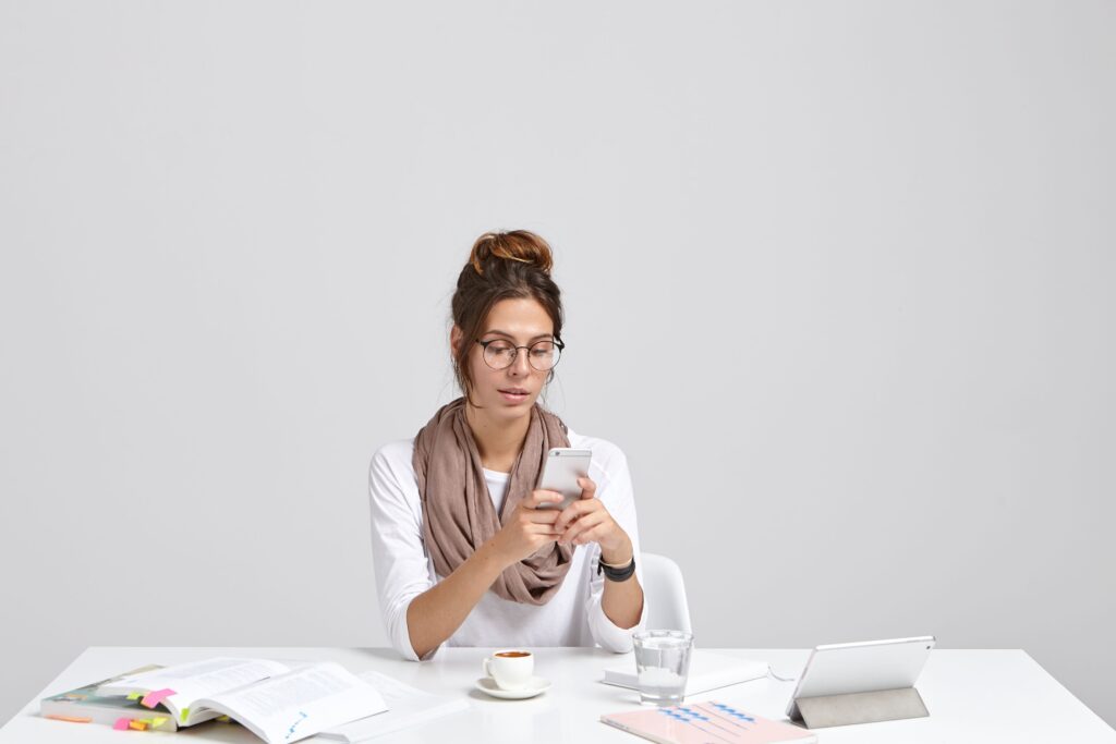Person sitting at a desk looking mentally overwhelmed while surrounded by smartphones, laptop screens, notifications, and digital information