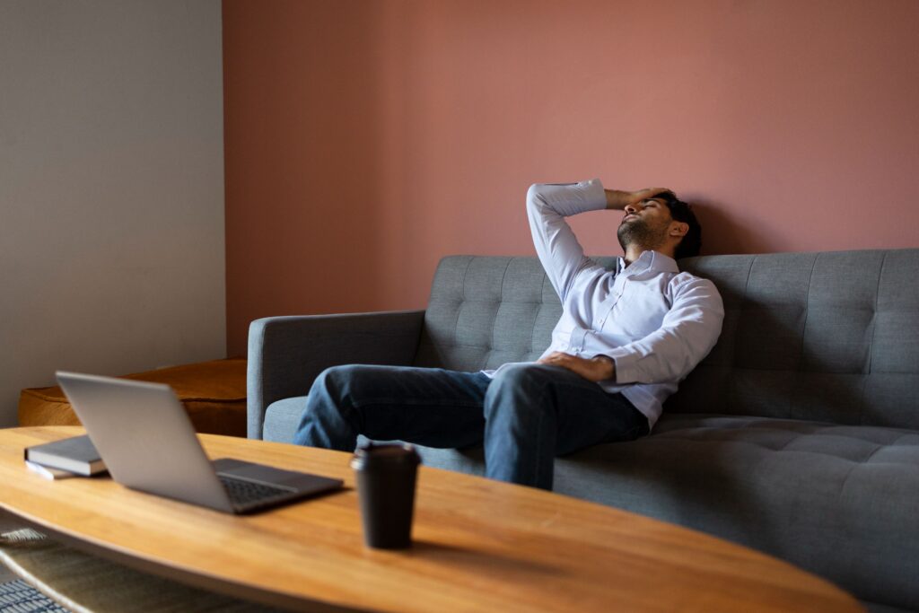 Person sitting quietly on a sofa while their mind appears busy with racing thoughts and unfinished tasks