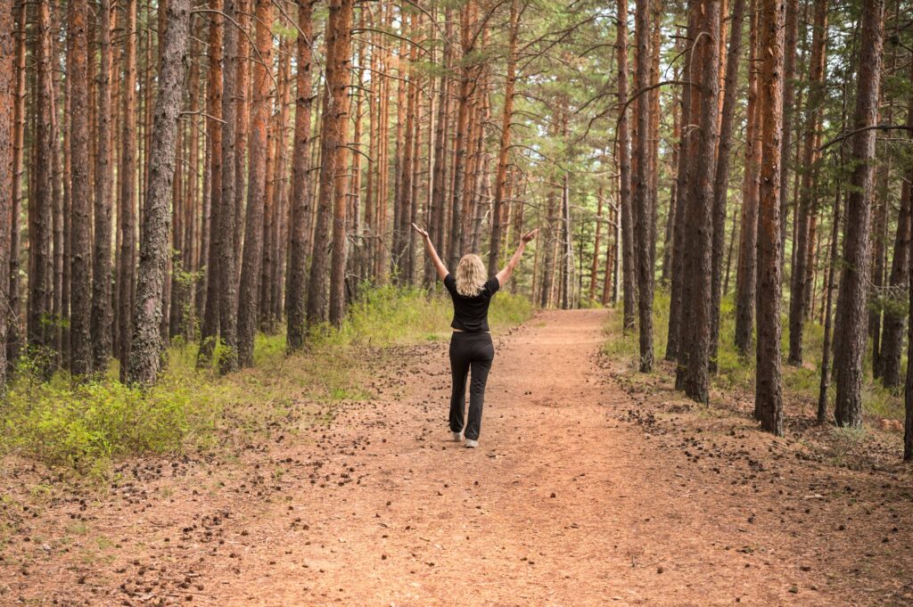 Person walking confidently along a peaceful forest trail after letting go of emotional burdens