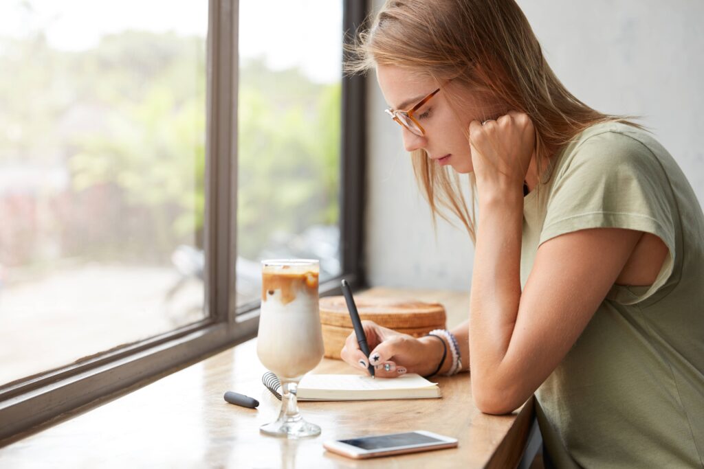 Person enjoying a peaceful morning with coffee and a journal while their smartphone remains untouched nearby