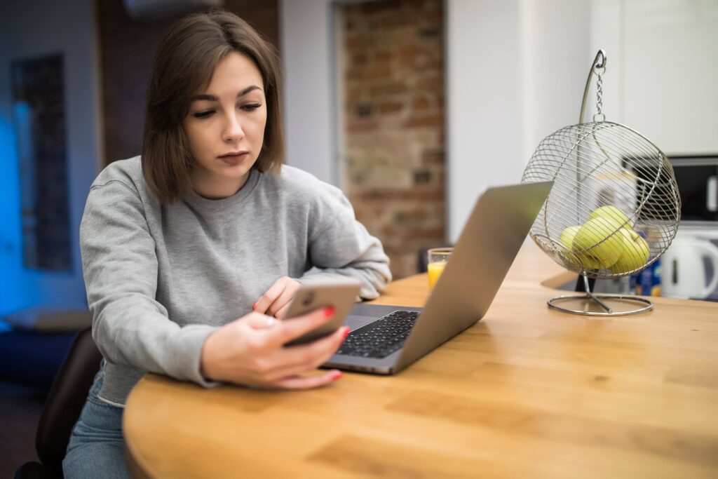 Professional working on a laptop while multiple smartphone notifications repeatedly interrupt their focus