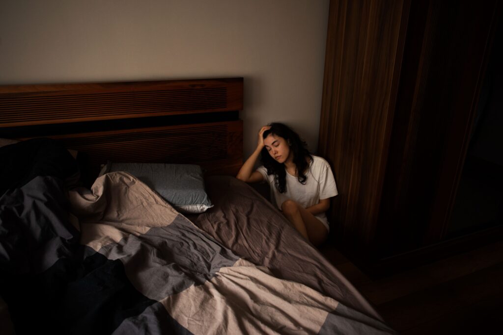 Person lying awake in bed while struggling with anxious thoughts during the night
