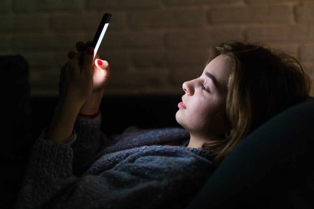 Tired woman continuing to scroll on her phone despite feeling mentally exhausted