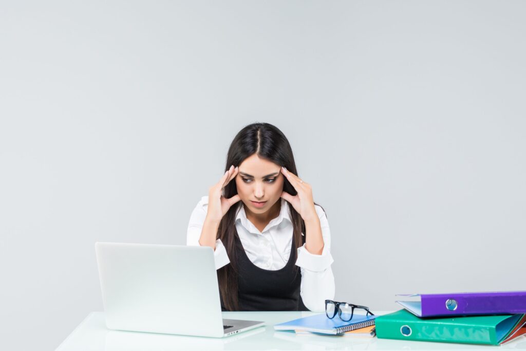 Office worker holding their head while experiencing physical tension and workplace stress