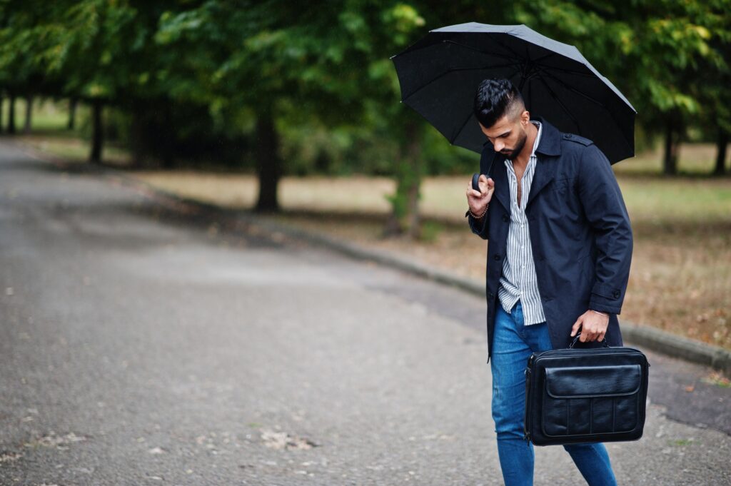 Person standing thoughtfully while carrying an invisible emotional burden represented by a heavy backpack