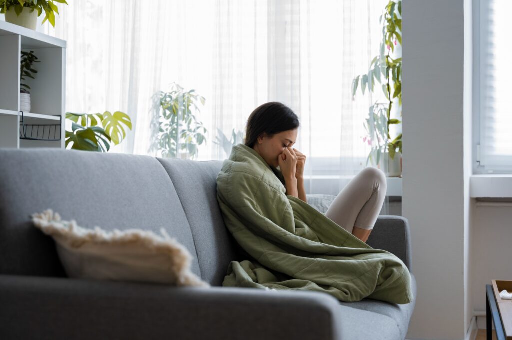 Person sitting quietly alone at home while reflecting on unresolved emotions