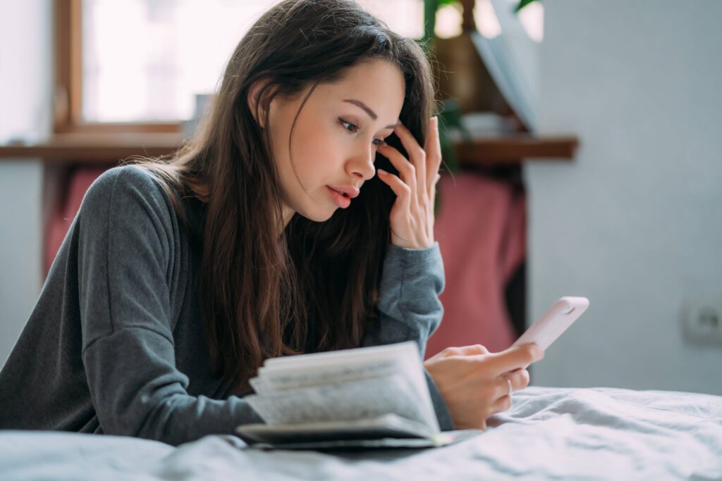 Person repeatedly checking their phone while waiting for important news, looking anxious and emotionally drained