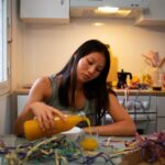 Person looking overwhelmed while dealing with a small everyday inconvenience in a kitchen, appearing emotionally exhausted