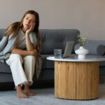Person sitting comfortably at home while looking mentally tense despite having no urgent responsibilities